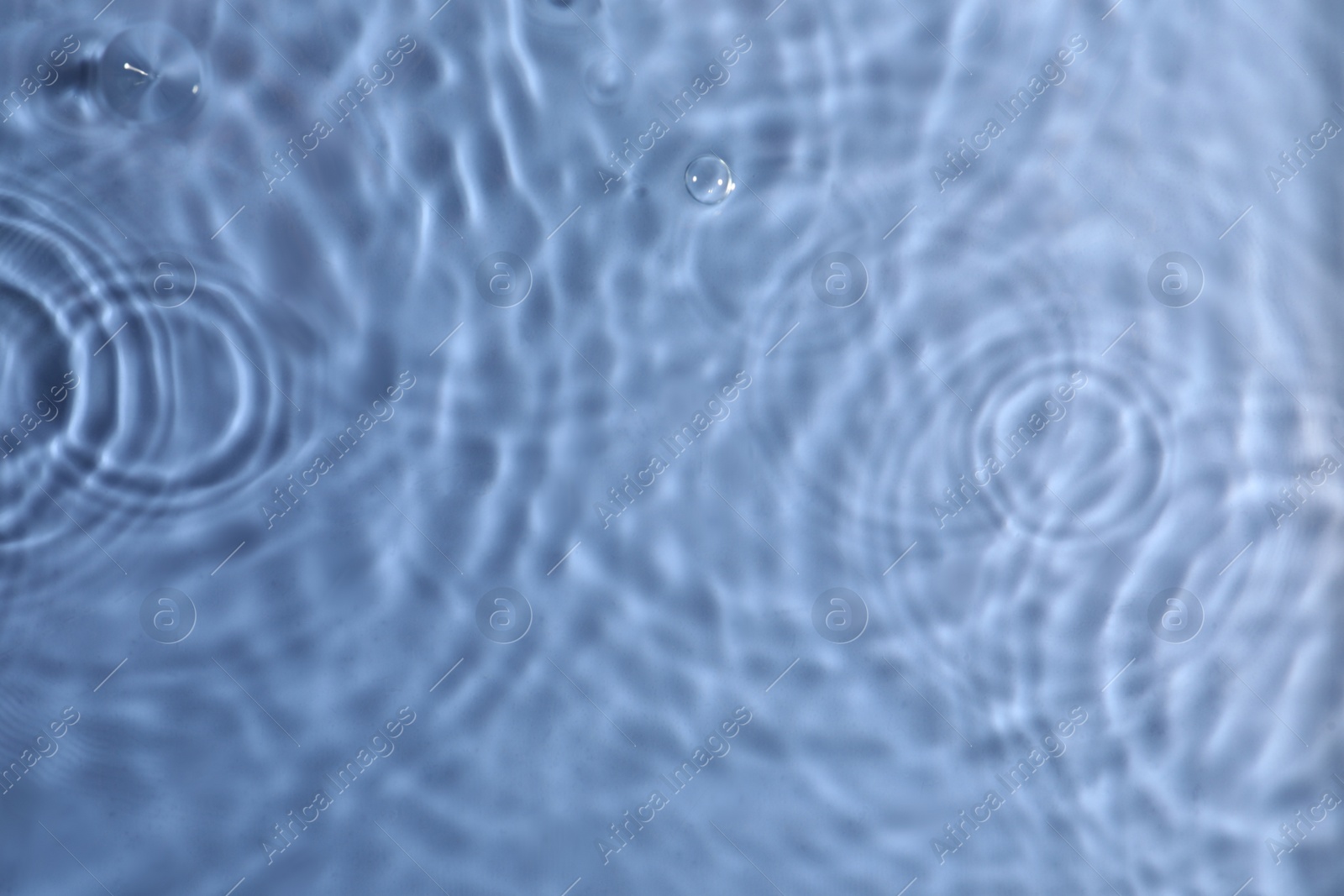 Photo of Closeup view of water with rippled surface on blue background