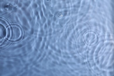 Photo of Closeup view of water with rippled surface on blue background