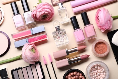 Photo of Flat lay composition with different makeup products and beautiful spring flowers on beige background