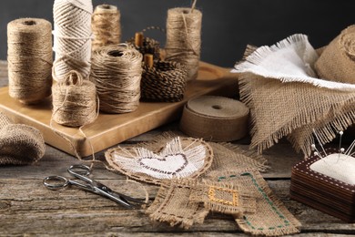 Pieces of burlap fabric, spools of twine and different sewing tools on wooden table