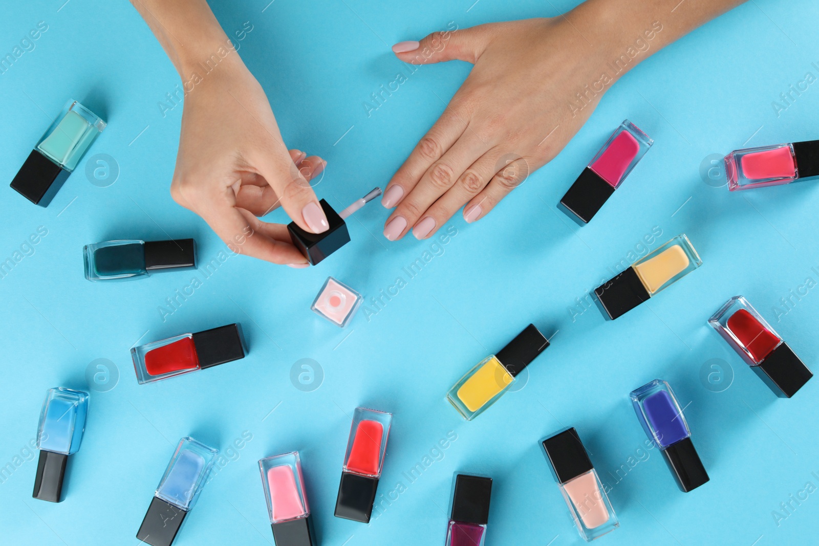 Photo of Woman applying nail polish on color background, above view