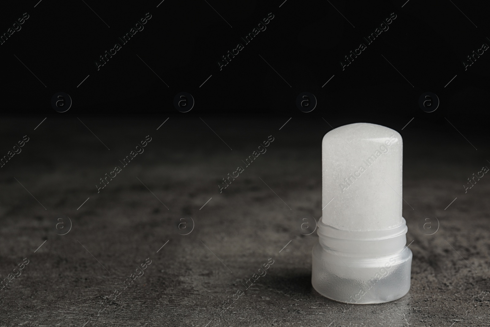 Photo of Natural crystal alum deodorant on grey table, space for text