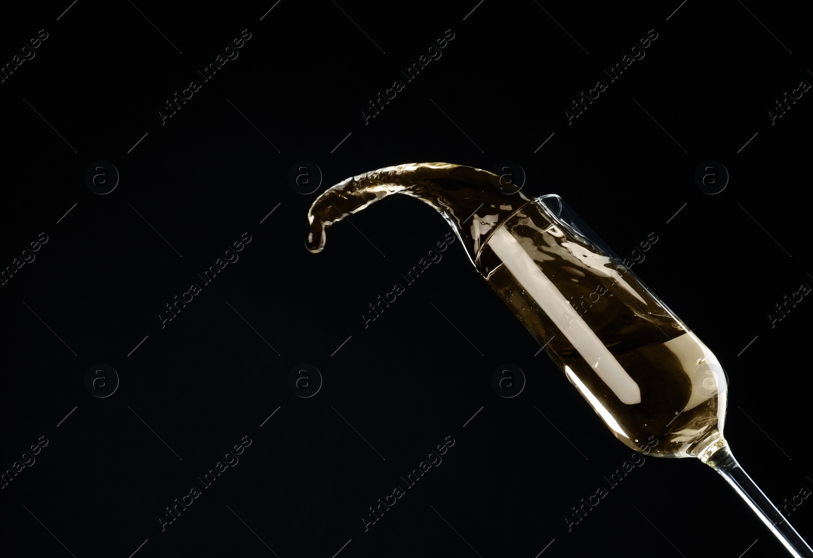 Photo of Sparkling wine splashing out of glass on black background