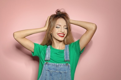 Beautiful young woman with healthy long blonde hair on color background