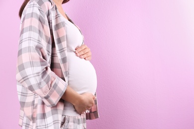 Pregnant woman posing on color background, closeup. Space for text