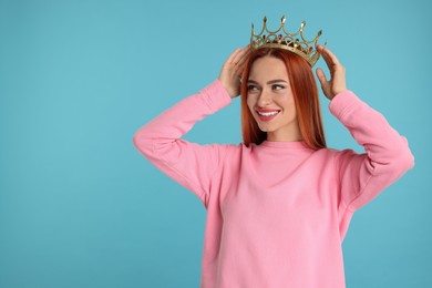 Photo of Beautiful young woman with golden crown on light blue background, space for text