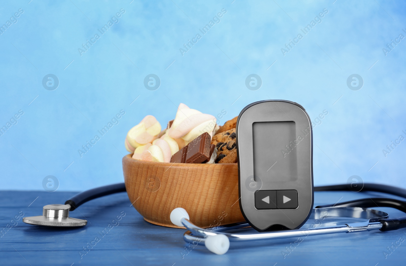 Photo of Digital glucometer, stethoscope and sweets on table. Diabetes concept