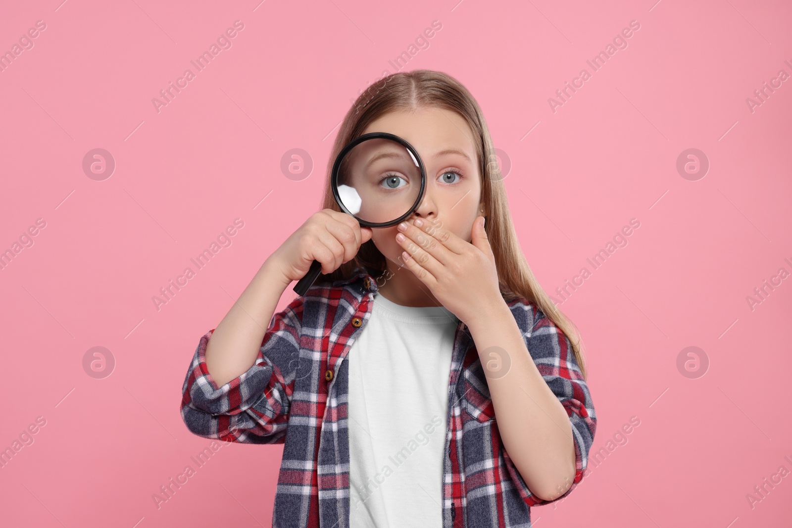 Photo of Cute little girl looking through magnifier on pink background