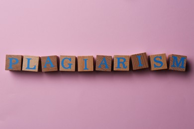 Wooden cubes with word Plagiarism on pink background, flat lay