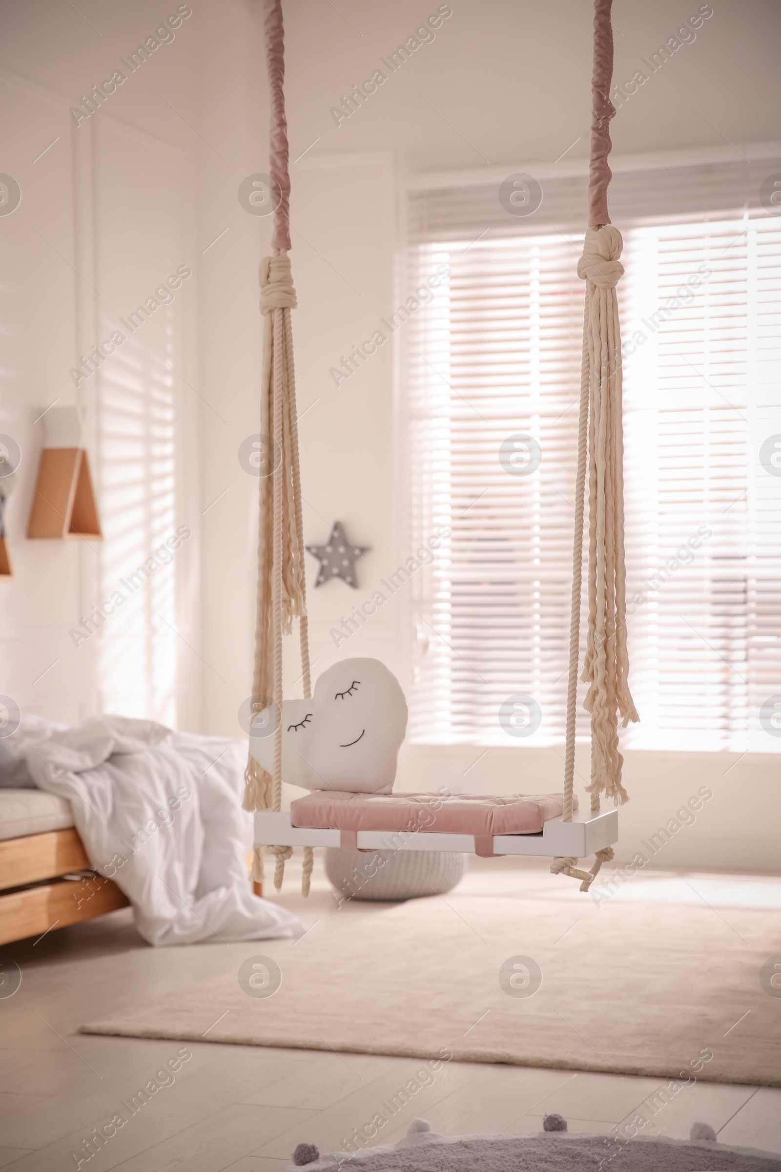 Photo of Beautiful swing with toy heart in bedroom. Stylish interior design