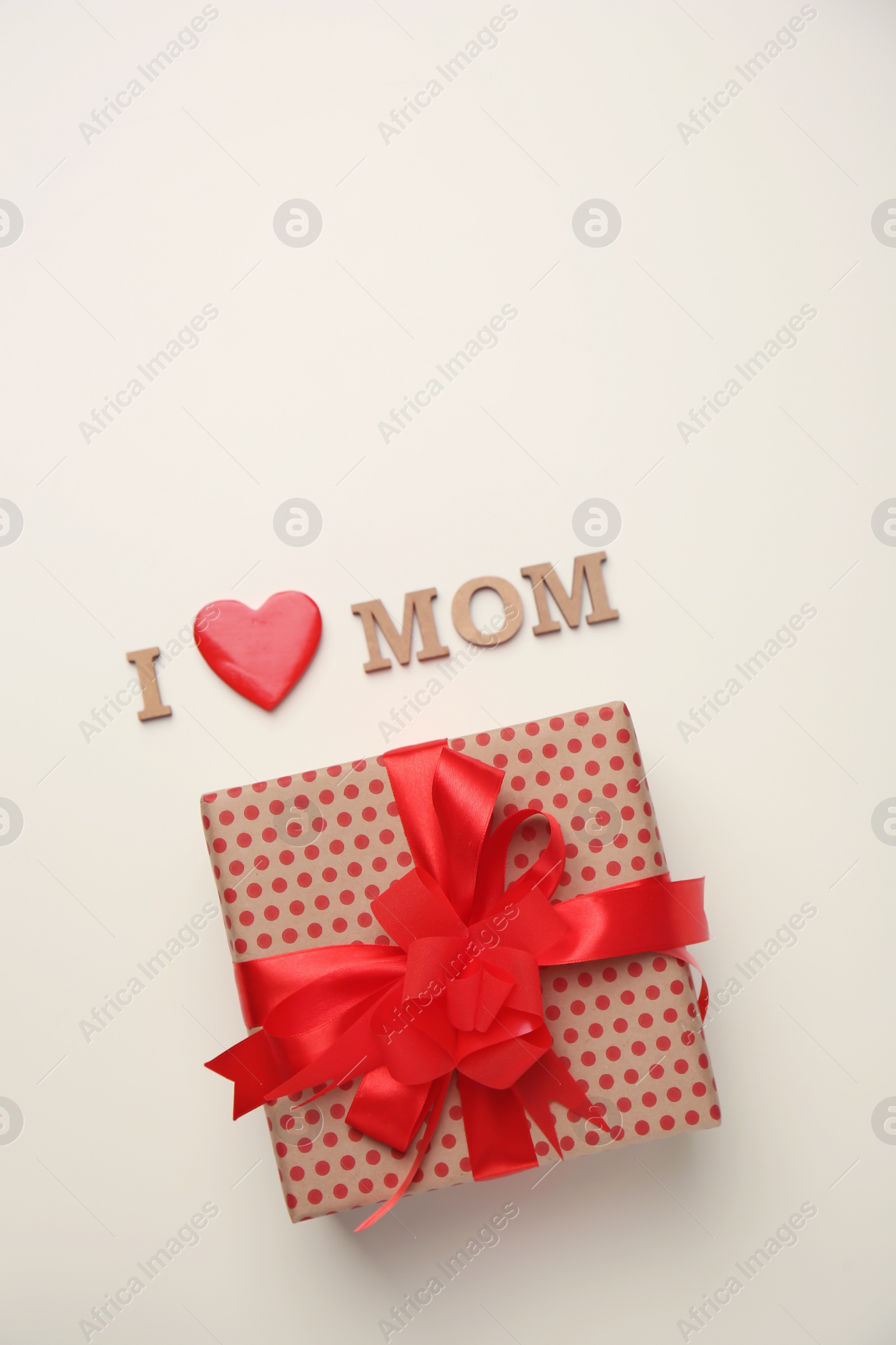 Photo of Flat lay composition with phrase I LOVE MOM and gift box for Mother's Day on light background