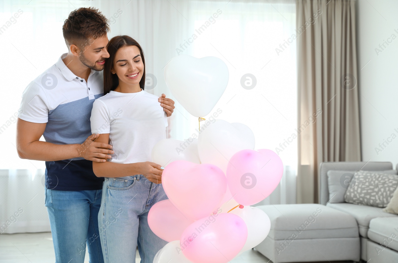 Photo of Young couple with air balloons at home. Celebration of Saint Valentine's Day