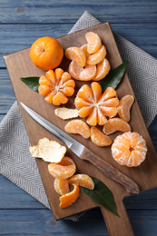 Photo of Fresh ripe tangerines on blue wooden table, top view