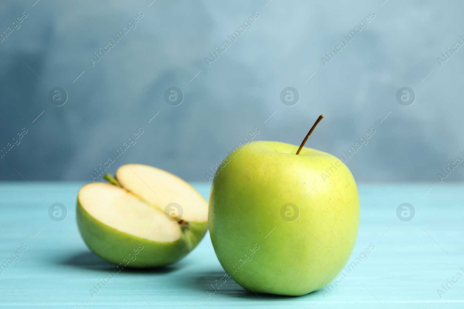 Photo of Fresh ripe green apples on wooden table against blue background, space for text