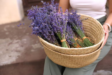 Woman with basket of beautiful lavender flowers outdoors, closeup