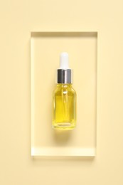 Photo of Bottle of cosmetic serum on beige background, top view