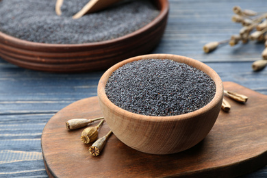 Photo of Poppy seeds in bowl on blue wooden table