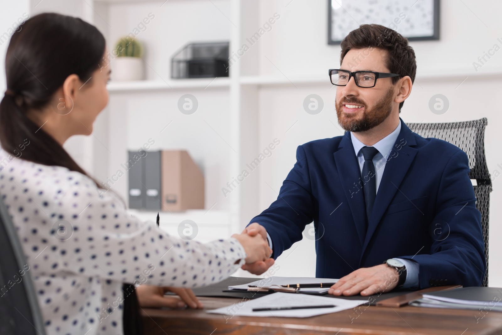 Photo of Lawyer shaking hands with client in office, selective focus