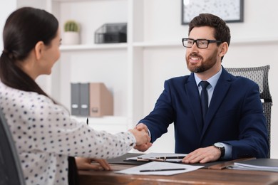 Lawyer shaking hands with client in office, selective focus