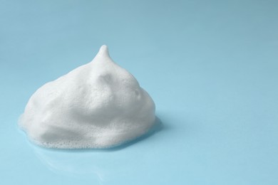 Photo of Foam on light blue background, space for text. Face cleanser, skin care cosmetic