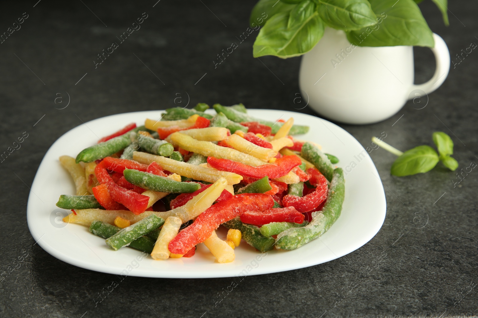 Photo of Mix of different frozen vegetables on gray table, closeup