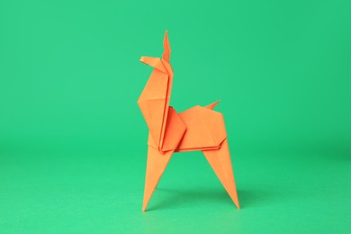 Photo of Origami art. Handmade orange paper deer on green background
