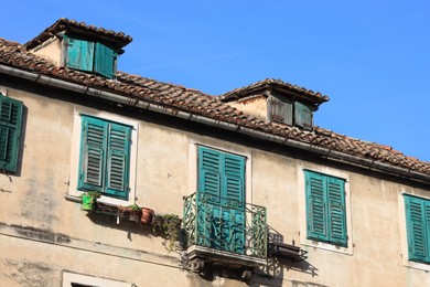 Old residential building with balcony against light blue sky