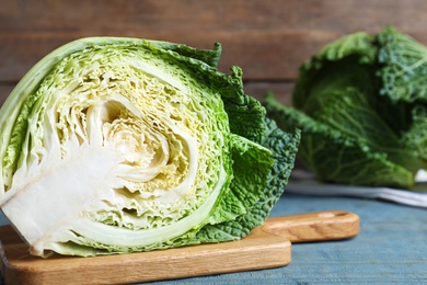 Photo of Half of fresh savoy cabbage on blue wooden table, closeup