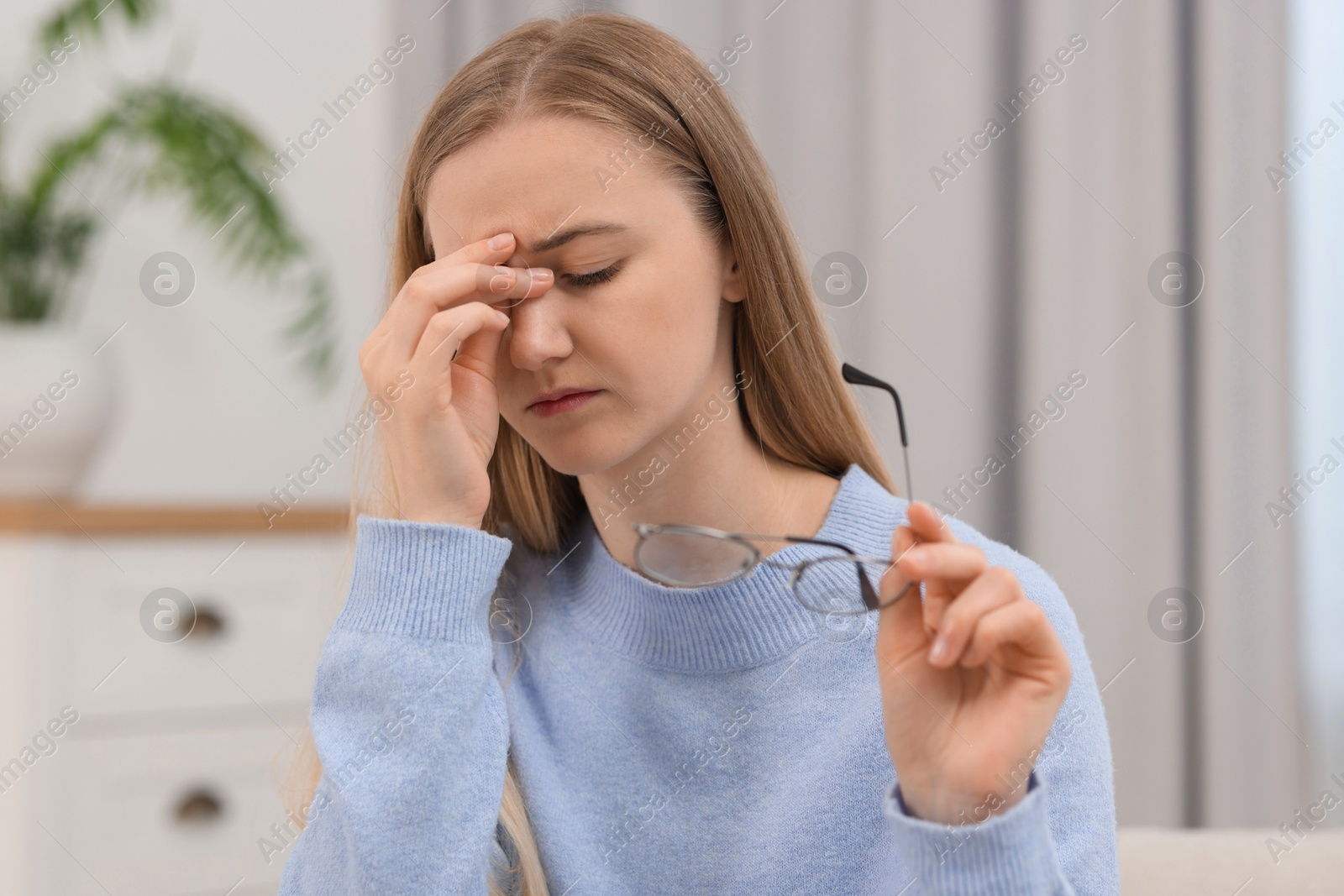 Photo of Overwhelmed young woman with glasses suffering from headache at home