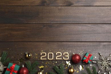 Photo of Flat lay composition with number 2023 and festive decor on wooden background, space for text. Happy New Year