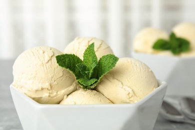 Photo of Delicious vanilla ice cream with mint in bowl on table, closeup