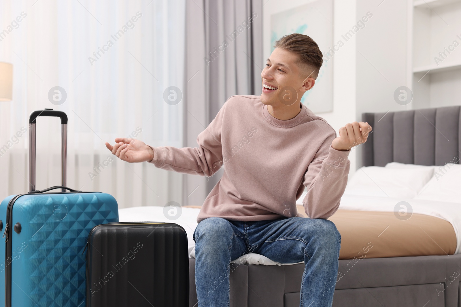 Photo of Smiling guest relaxing on bed in stylish hotel room