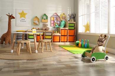 Photo of Stylish playroom interior with soft toys and modern furniture