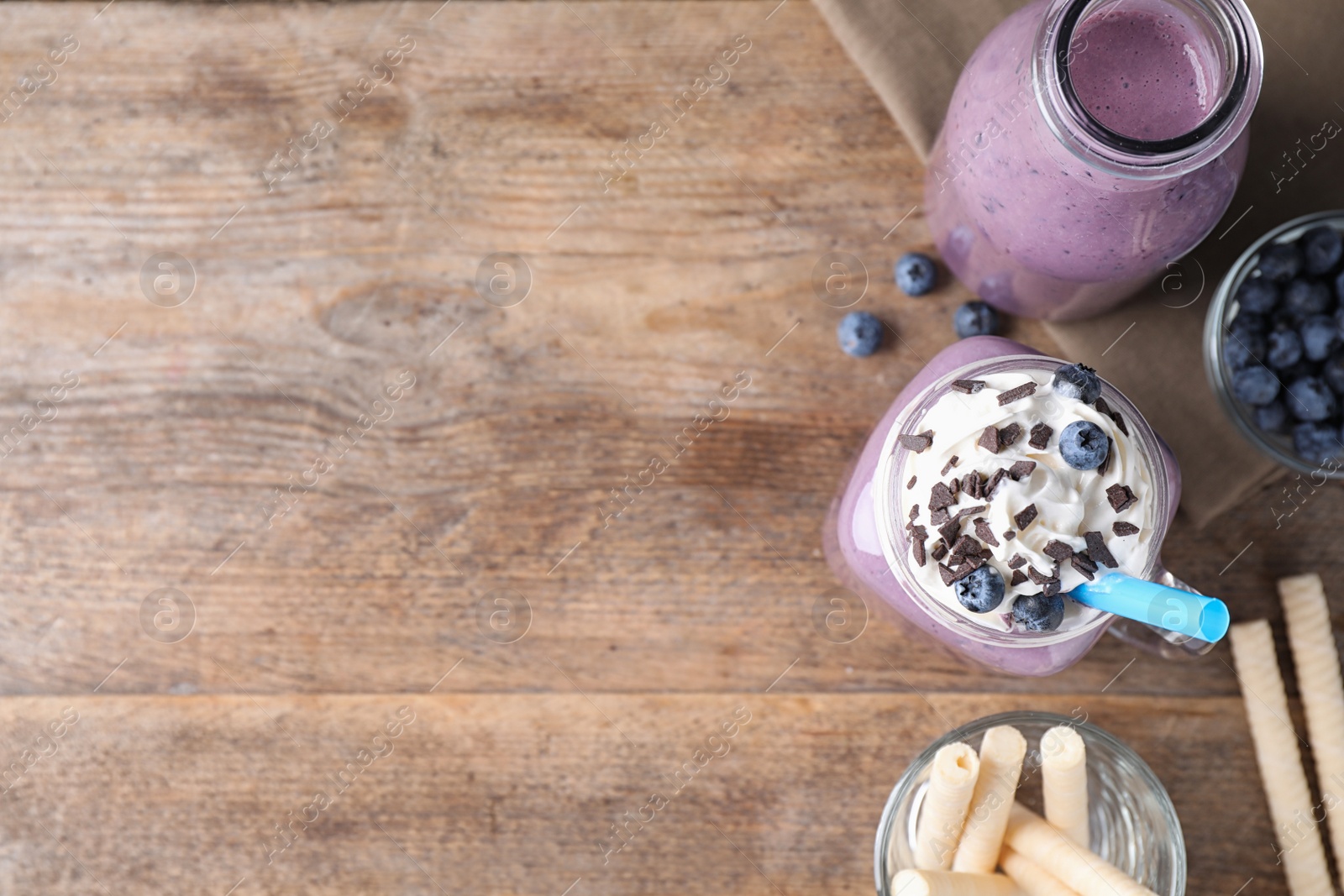 Photo of Tasty blueberry milk shake served on wooden table, flat lay. Space for text