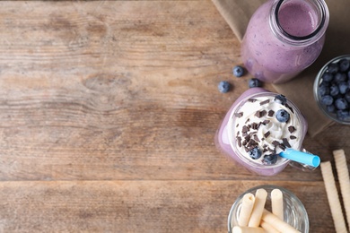 Tasty blueberry milk shake served on wooden table, flat lay. Space for text