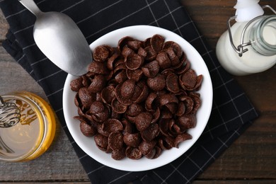 Photo of Chocolate corn flakes served with milk and honey on wooden table, flat lay. Breakfast cereal