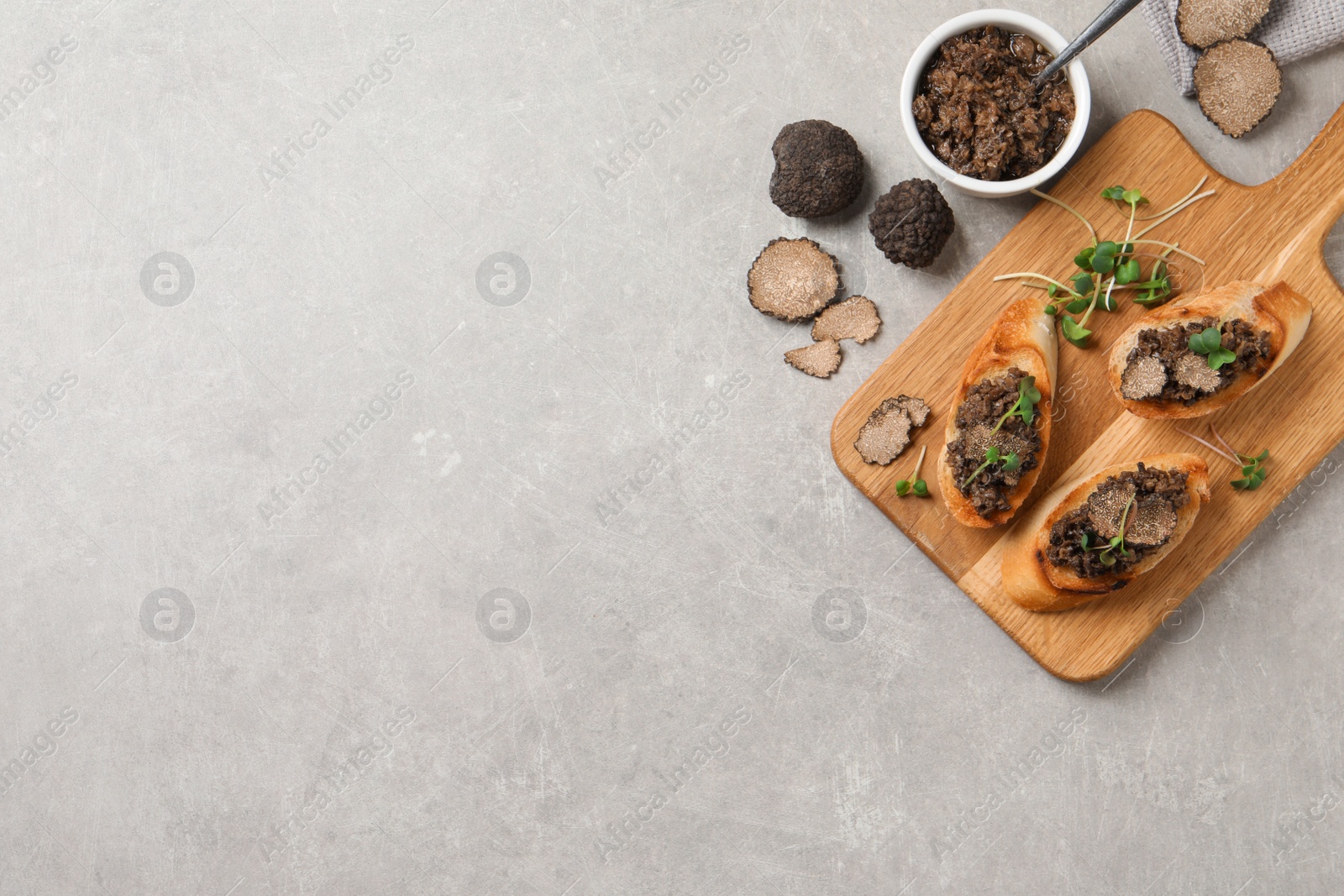 Photo of Tasty bruschettas and truffle paste on grey table, flat lay. Space for text