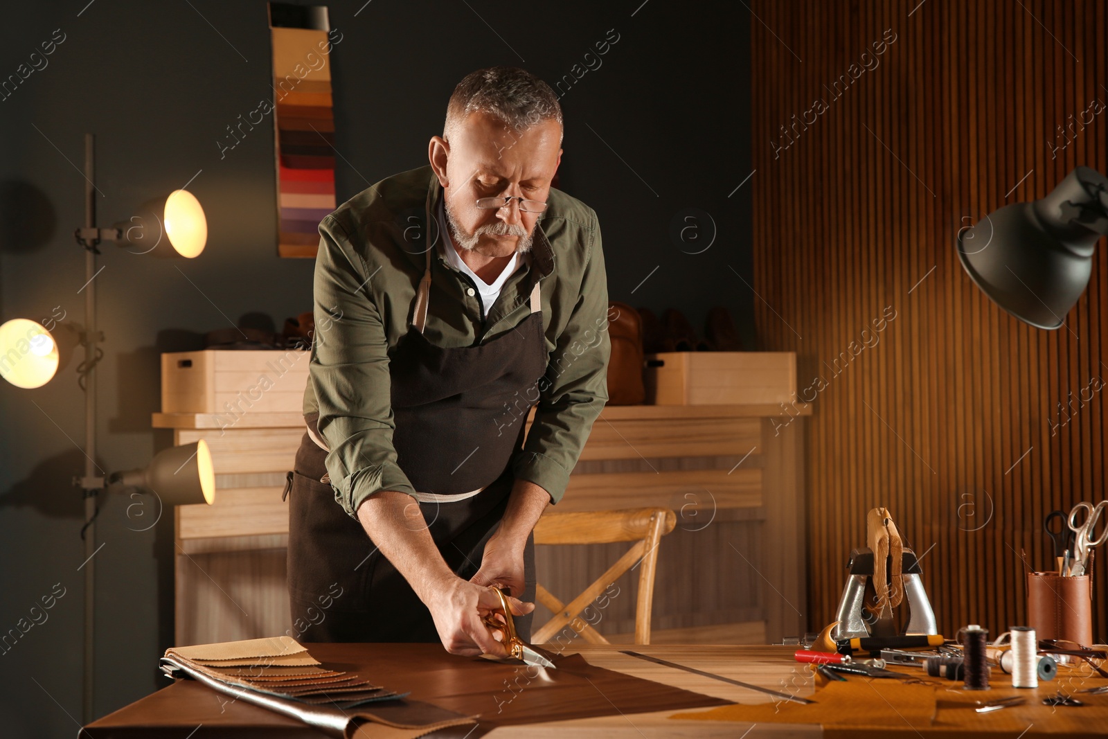 Photo of Man cutting leather with scissors in workshop