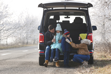 Happy family with little children near modern car on road