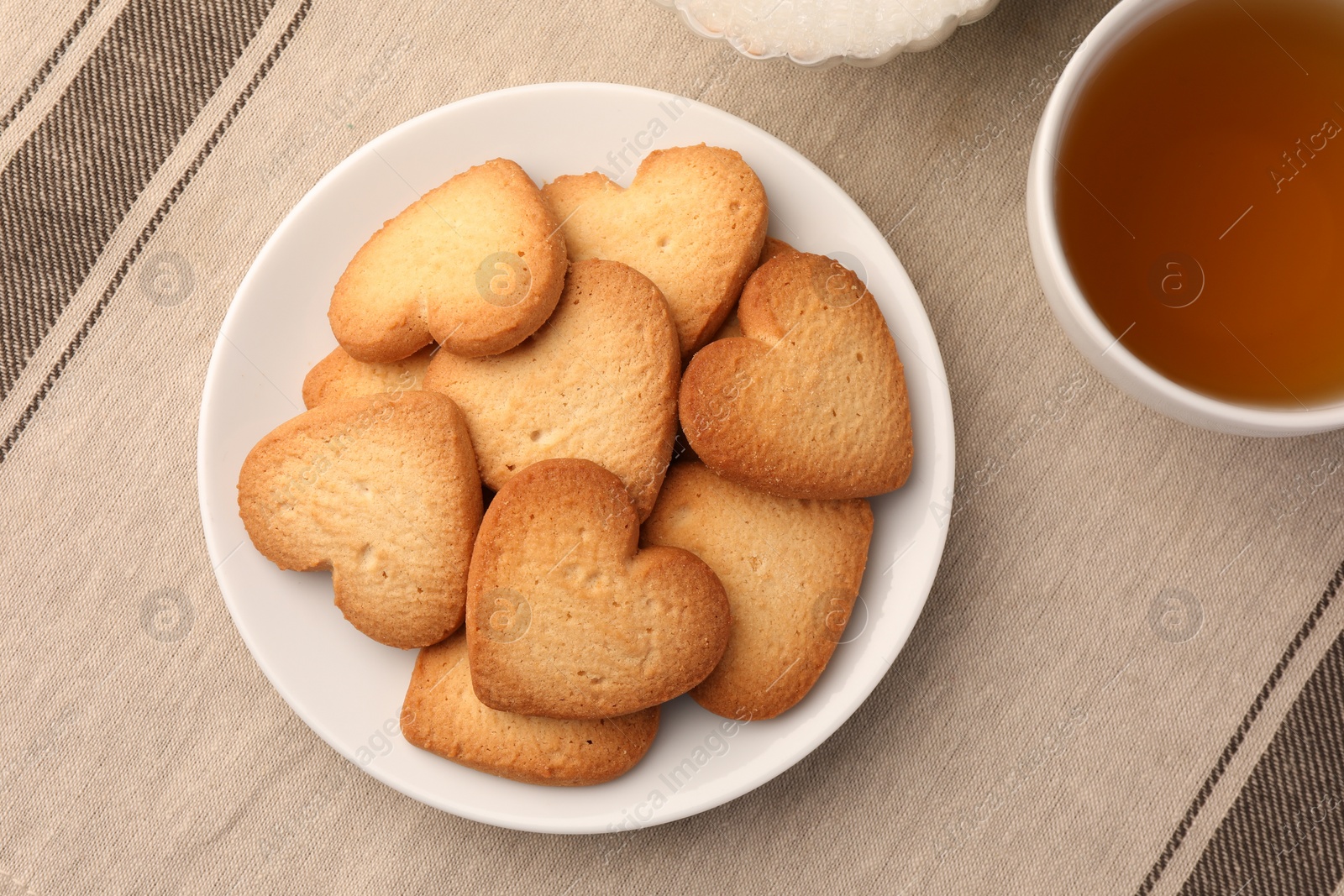 Photo of Heart shaped Danish butter cookies and tea on table, flat lay