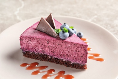 Plate with piece of tasty blueberry cake on gray table