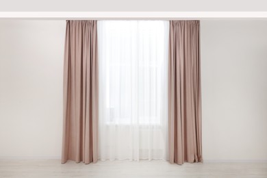 Photo of Elegant window curtains and white tulle indoors. Interior design