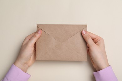 Photo of Woman with brown envelope on beige background top view