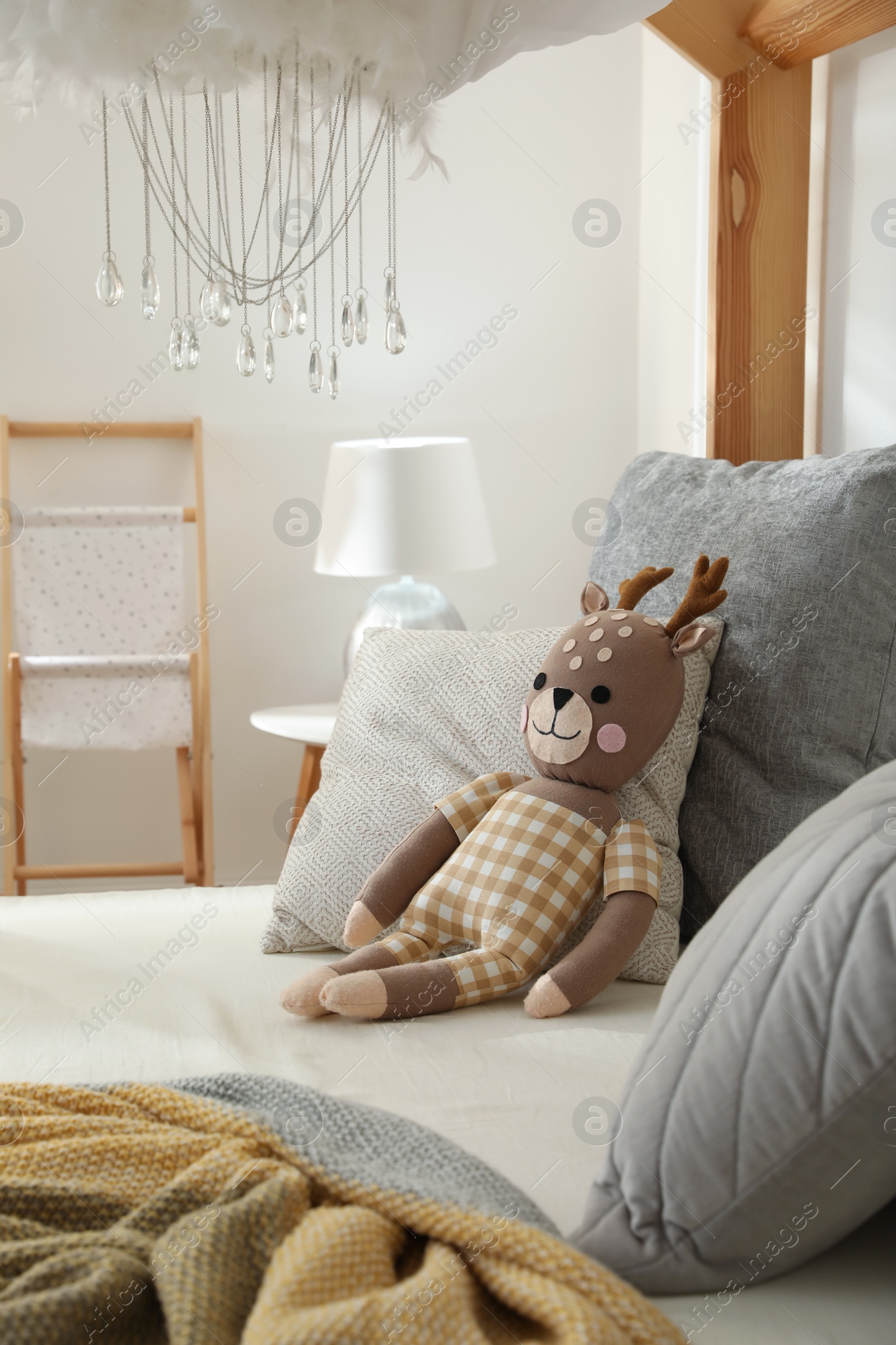 Photo of Comfortable wooden house bed with cushions and toy in child room. Interior design