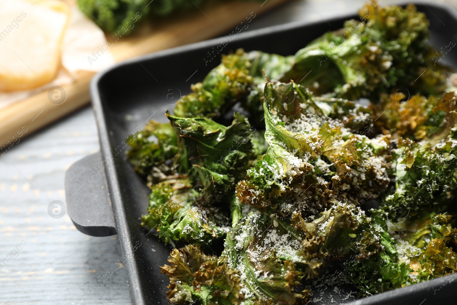 Photo of Tasty baked kale chips on grey table, closeup