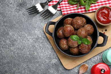 Photo of Tasty cooked meatballs with basil served on grey table, flat lay. Space for text