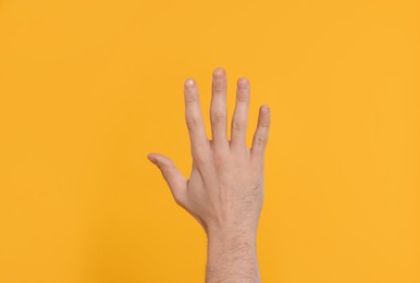 Photo of Man giving high five on yellow background, closeup of hand