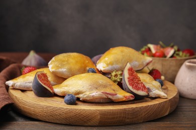 Delicious samosas with figs and berries on wooden table