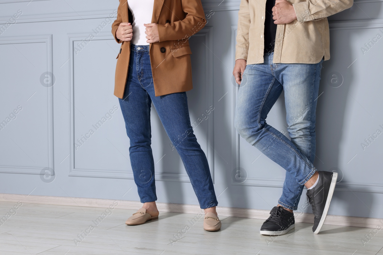 Photo of People in stylish jeans near light grey wall indoors, closeup