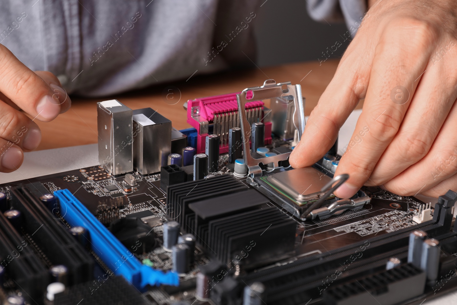 Photo of Technician repairing computer motherboard at table, closeup. Electronic device